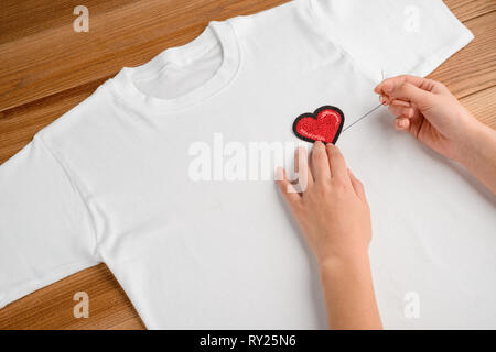 Girl applying embroidered heart patch Stock Photo