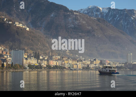 Montreux, Switzerland - 02 17, 2019: Ship cruising towards Montreux with mountains in the background. Stock Photo