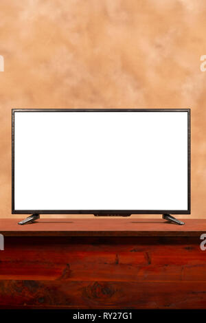 Vertical shot of a blank large screen tv with copy space on table.  Brown muddled background. Stock Photo
