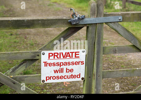 Warning sign on a wooden, timber, farm field gate. PRIVATE, Trespassers will be prosecuted. Gate is padlocked. Owners fear of domestic livestock theft and vandalism. Stock Photo