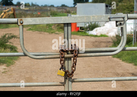 Metal Gates, closed and secured by a heavy-duty metal chain and padlock. Property protection. Practical and, by sight, psychological thinking on the wayward passersby. Stock Photo