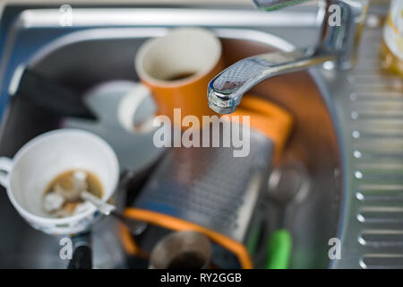 A pile of dirty and unwashed dishes in the sink close-up. Leftover coffee in glasses. Stock Photo