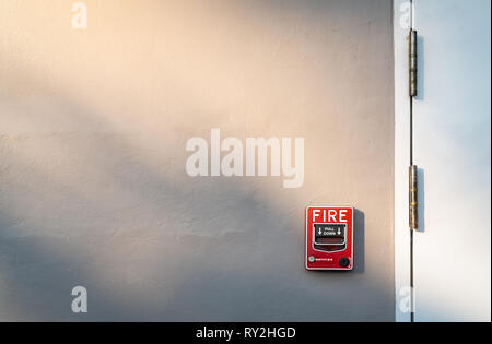 Fire alarm on dark gray concrete wall. Warning and security system. Emergency equipment for safety alert. Red box of fire alarm on wall of school, hos Stock Photo