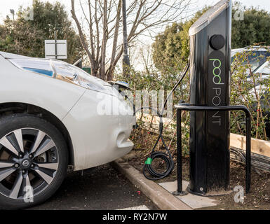 Nissan electric car being recharged in parking lot Stock Photo