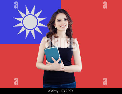 Portrait of happy pretty girl against the Taiwan flag background. Young woman learning chinese language and traveling in Taiwan Stock Photo