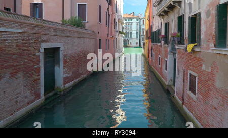 One of the many small lagoons in the grand canal with the tall buildings on the side of the canal in Venice Italy Stock Photo
