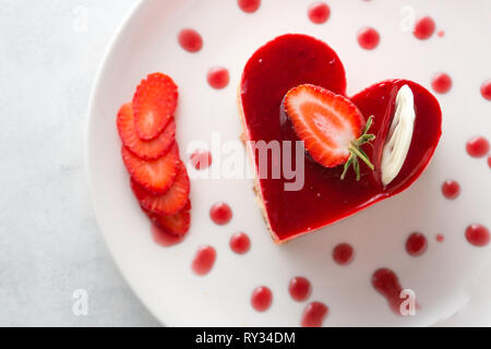 Heart Cake picture . Lovely delicious heart cake. A red colored cheesecake on a plate and a wooden table. Stock Photo