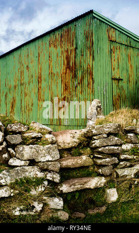 Dry stone wall with stone steps in front of green rusty corrugated shed St Breward Bodmin moor Cornwall Stock Photo
