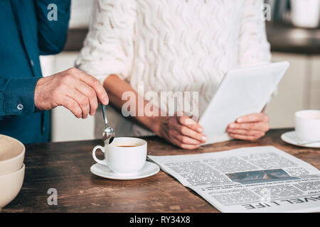 cropped view of man holding spoon near cup with coffee near wife holding digital tablet Stock Photo