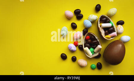 Delicious chocolate easter eggs, sweets on bright yellow background Stock Photo
