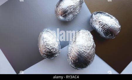 Eggs in foil on silver background. Easter concept banner Stock Photo