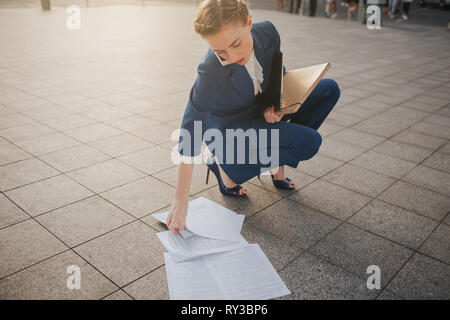 Overworked business woman having a lot of paperwork. Business woman surrounded by lots of papers. Business woman standing in the heap of papers. Stock Photo