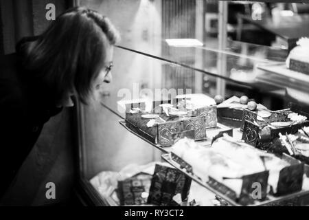 Woman buying sweets a the patisserie bakery store window in French city during Christmas winter holidays  Stock Photo