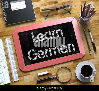 Learn German on Small Chalkboard. Learn German - Red Small Chalkboard with Hand Drawn Text and Stationery on Office Desk. Top View. 3d Rendering. Stock Photo