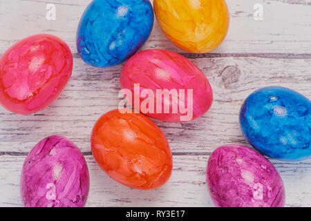 top view on colored easter eggs on a white wooden surface, macro color photo with copy space Stock Photo