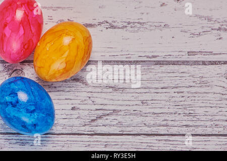 top view on colored easter eggs on a white wooden surface, macro color photo with copy space Stock Photo