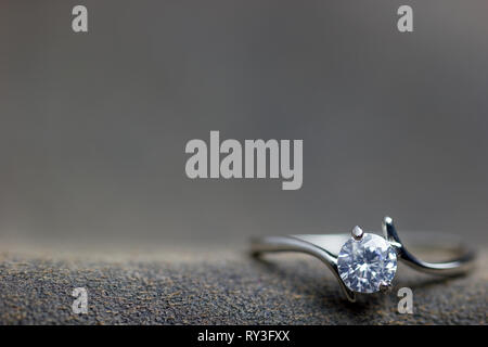 Closeup fake diamond ring placed on brown leather jecket. The concept of love or marriage. Copy space can be used to write articles about Valentine's  Stock Photo