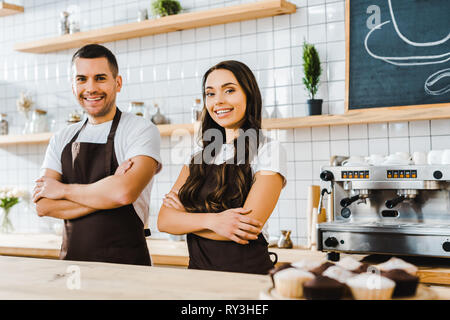 cashiers standing behind bar counter and smiling in coffee house Stock Photo