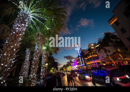 MIAMI - DECEMBER 30, 2018: Visitors stroll along the lights of Ocean Drive, with Art Deco neon lights and holiday palm trees decorated for Christmas. Stock Photo