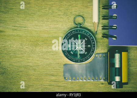 Compass photographic film and notebook with pencil placed on brown wooden table. The concept of tourism planning. Stock Photo