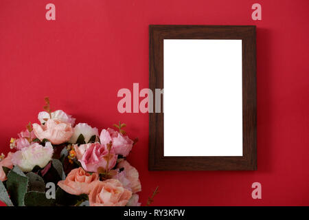 Mock-up wooden photo frame with space for text or picture on red background and flower Stock Photo