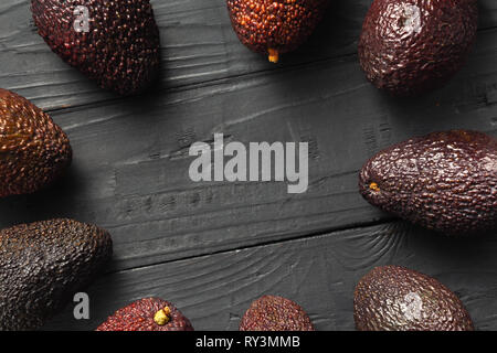 Frame of fresh avocado hass on wooden dark background top view Stock Photo