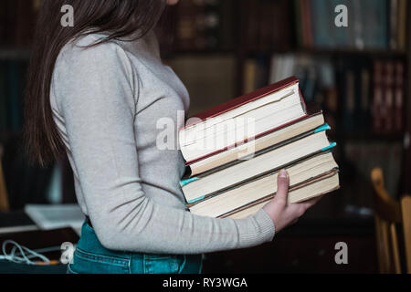 Close up view of student girl holding books while standing at the library Stock Photo