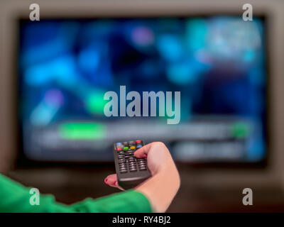 Remote control in a woman's hand with red nail polish Stock Photo