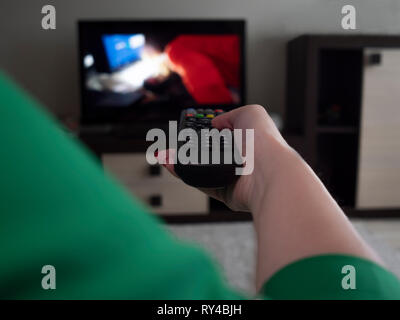 Female hand with tv remote control, rear view Stock Photo