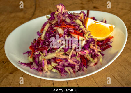 Autumn salad. With white and red cabbage, grated carrots and red beets, dill and olive oil. Garnished with slice of lemon. Stock Photo