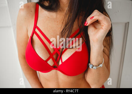 Close up of breast of woman presenting her bra. Red bra. Sexy boobs. Woman  with big natural sexy boobs in lingerie. Closeup of sexy female boob in red  bra. Red colored nails