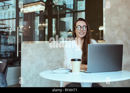 Woman entrepreneur working from cafe and talking on mobile phone Stock Photo
