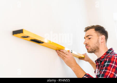 serious handyman measuring wall at home