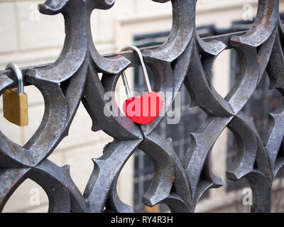 Padlock red heart shaped locked onto a wrought iron railing Stock Photo