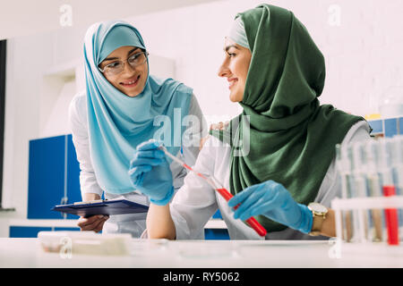 smiling female muslim scientists in hijab with test tube and pipette ...