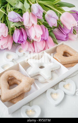 Biscuit gingerbread cookies in the shape of a star and heart against the backdrop of a beautiful festive bouquet of tulips Stock Photo