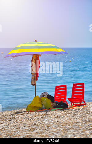 Pair of sun loungers and a beach umbrella on a deserted beach; perfect vacation concept Stock Photo
