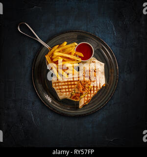 Wrap with grilled chicken served with chili sauce and french fries Stock Photo