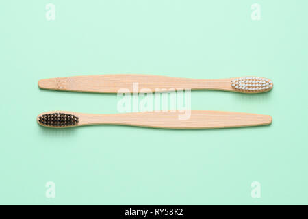 Bamboo toothbrushes on light green background top view Stock Photo