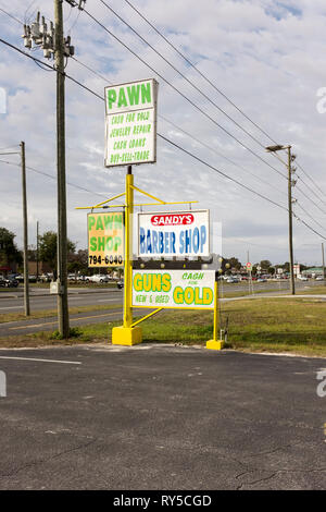 Signs advertising various businesses including a barber shop and pawn shop outside a roadside strip mall in Homosassa Springs, Florida Stock Photo
