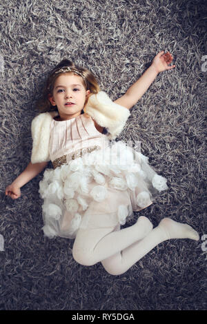 Little girl with beautiful dress lay on floor Stock Photo