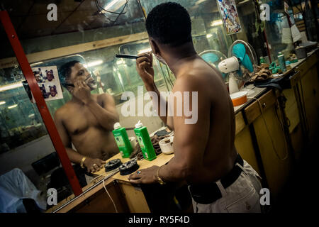 A young Cuban hairdresser shaves himself with a razor after a busy working day in a barber shop in Havana, Cuba. Stock Photo