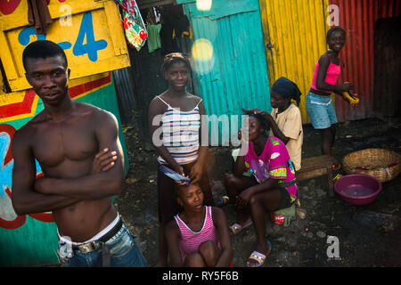 Young Haitian girls and women style their hair on the street inside a shanty town in Port-au-Prince, Haiti. Stock Photo