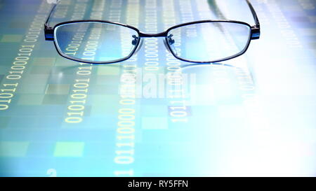 reading data in digital age. glasses and flowing binary code matrix. shallow depth of field image of glasses on display panel. multiple lines of blue  Stock Photo