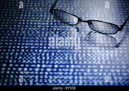 big data analysis. blue binary code on led panel with black background and glasses placed over the information panel. hacker and source code analysis. Stock Photo