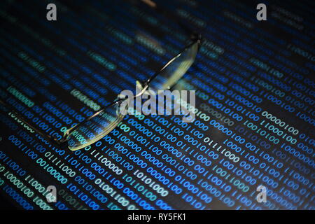 big data analysis. blue binary code on led panel with black background and glasses placed over the information panel. hacker and source code analysis. Stock Photo