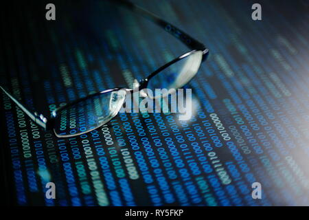 big data analysis. blue binary code on led panel with black background and glasses placed over the information panel. hacker and source code analysis. Stock Photo