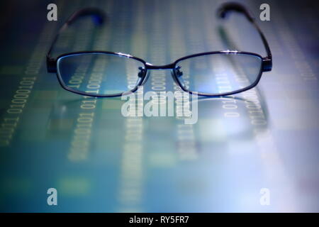 big data analysis. blue binary code on led panel with black background and glasses placed over the information panel. hacker and source code analysis. Stock Photo