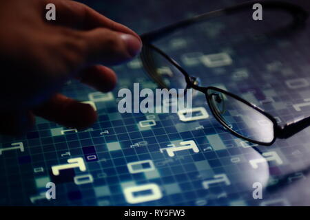 hand reaching for glasses on digital led displaying multiple layers of binary code computer data matrix. big data analytics and digital language conce Stock Photo
