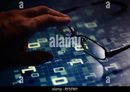 hand reaching for glasses on digital led displaying multiple layers of binary code computer data matrix. big data analytics and digital language conce Stock Photo